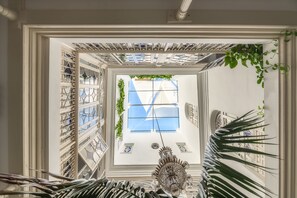 A room with a large window, a chandelier, and a view of the sky. - Hotel Casa de Colón (Seville)