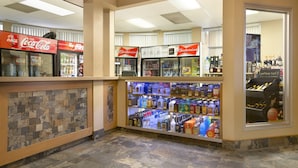 A beverage kiosk with Coca-Cola and Budweiser refrigerators, a display of liquor bottles, and a stone wall.
