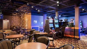 A hotel lobby with round tables, chairs, and slot machines.