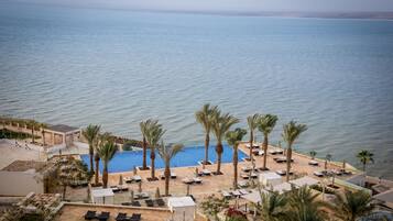 Ein Resort mit Poolbereich, Palmen und Meerblick.