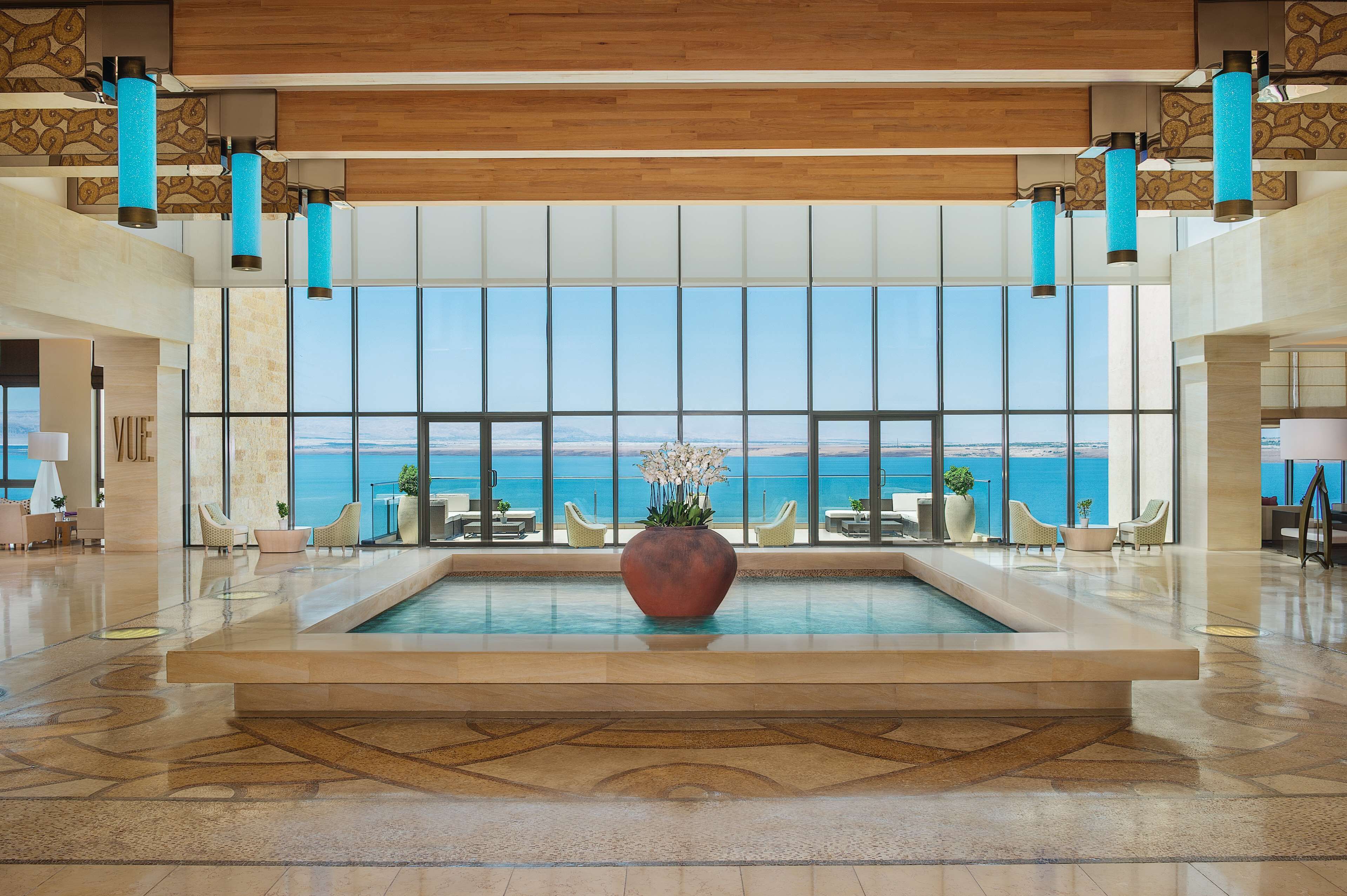 A spacious lobby with a large pool, seating area, and a view of the sea.
