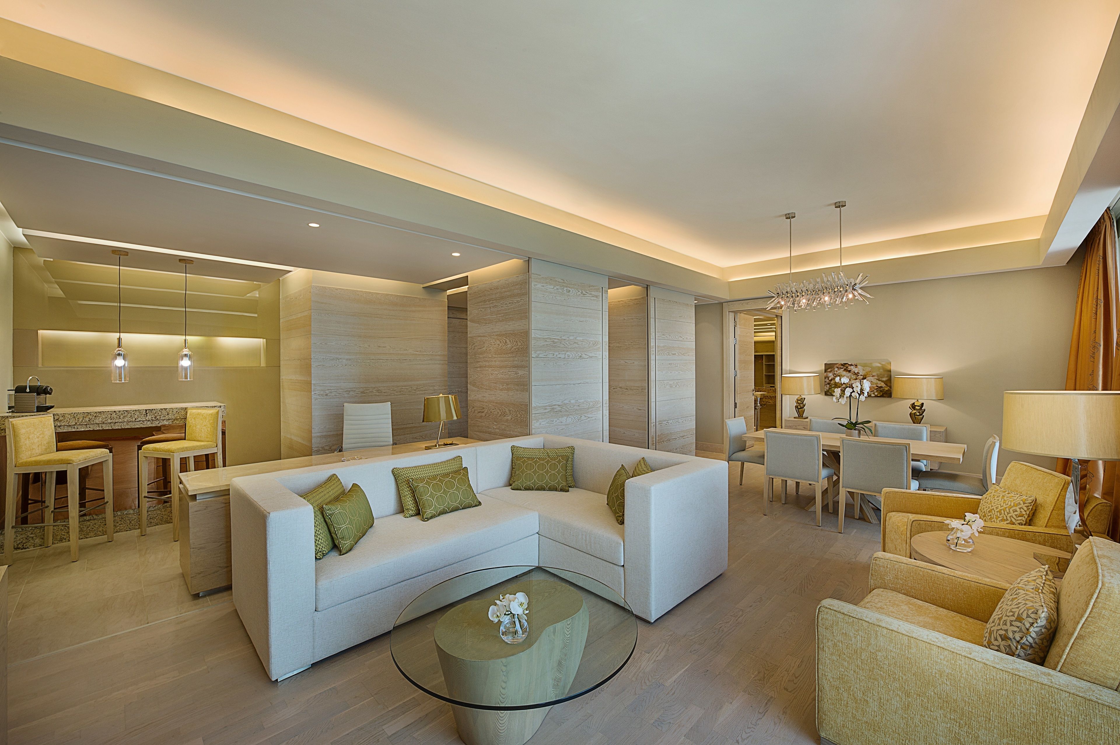 A modern living room with a sectional sofa, a glass coffee table, and a dining area with a table and chairs.
