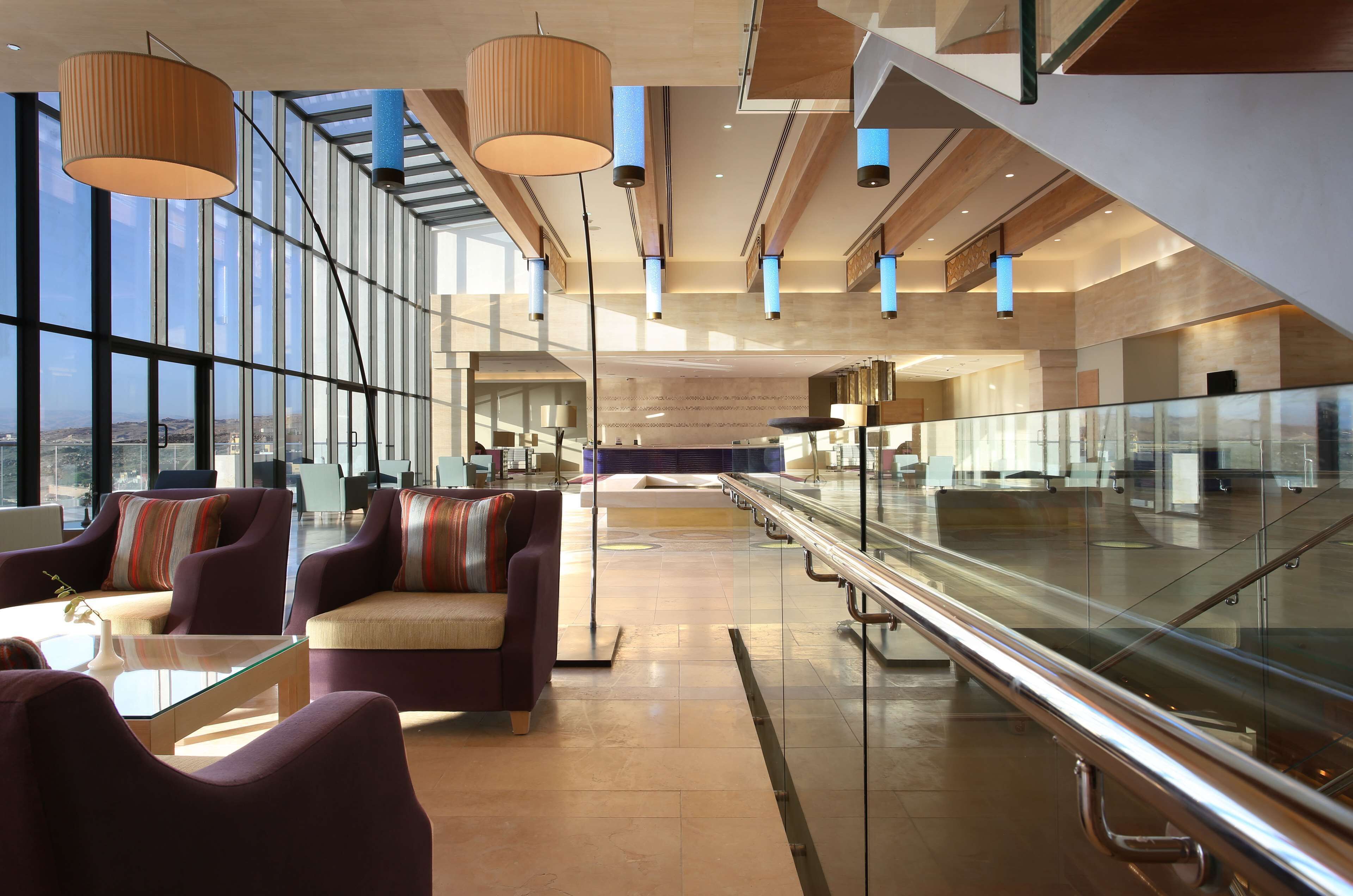 A spacious lobby with modern furnishings, large windows, and a glass railing.
