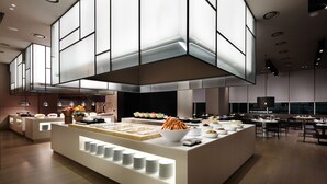 Un espace buffet moderne et bien éclairé, proposant une grande variété de plats et où les assiettes sont disposées avec soin.