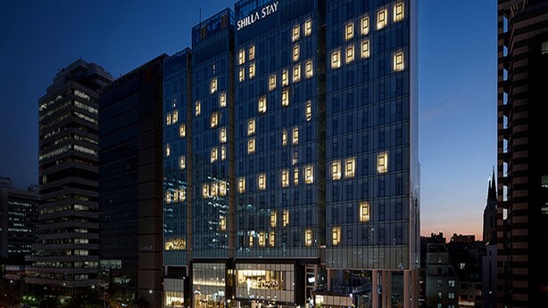 Un hôtel moderne doté d’une façade en verre, de plusieurs étages et de fenêtres illuminées.