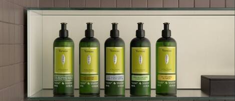 A bathroom shelf with five bottles of Vervine L'OCCITANE products.