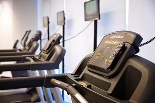 A row of treadmills with a control panel and a phone on one of them.