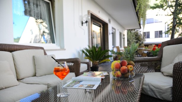 A glass-top table with a drink, a fruit bowl, and a magazine. - Pension Schweitzer (Silandro)