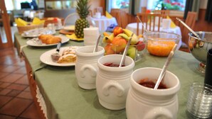 A breakfast buffet with various fruits, pastries, and beverages. - Pension Schweitzer (Silandro)