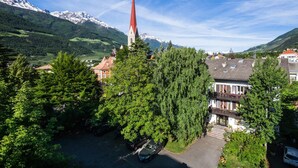 A church with a tall spire, surrounded by lush greenery and a mountain backdrop. - Pension Schweitzer (Silandro)