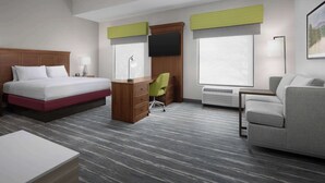 Une chambre d’hôtel équipée d’un lit, d’un bureau, d’une chaise, d’un canapé et de grandes fenêtres.