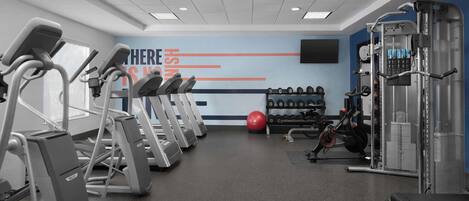 A gym with treadmills, a red exercise ball, and weight machines.