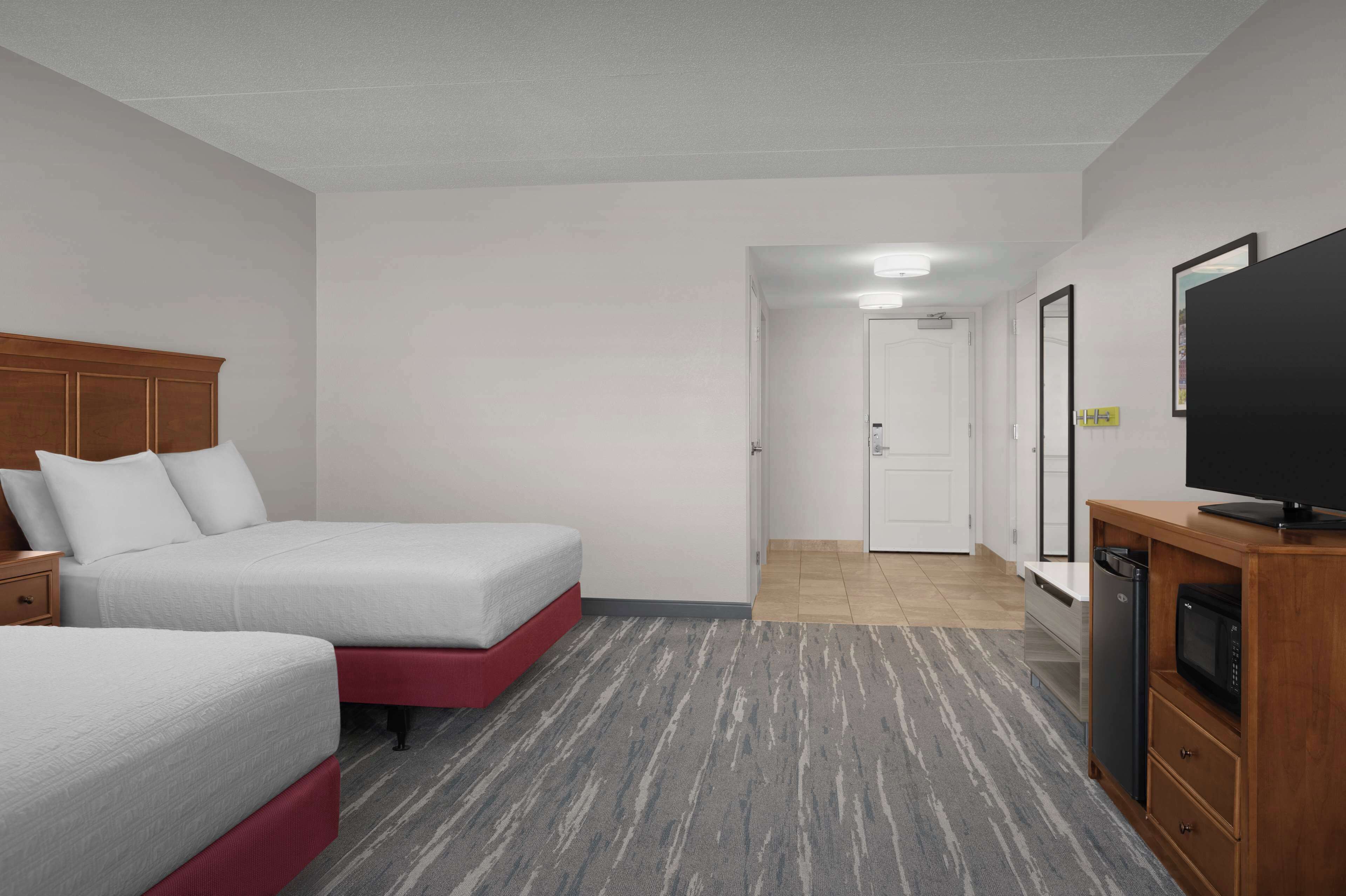 A hotel room with two beds, a TV, a microwave, and a bathroom visible through the door.