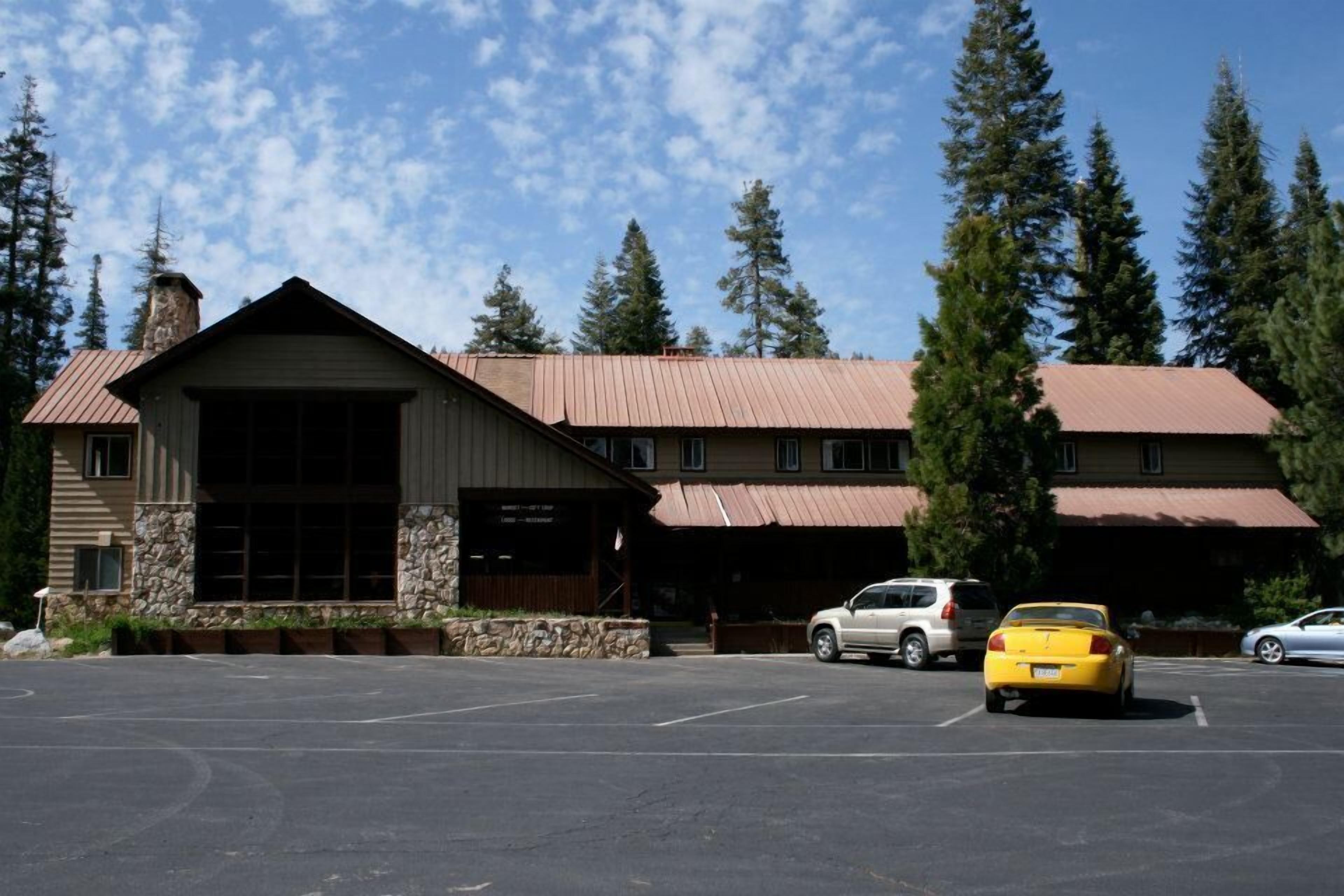 A lodge with a stone facade, large windows, and a covered parking area.