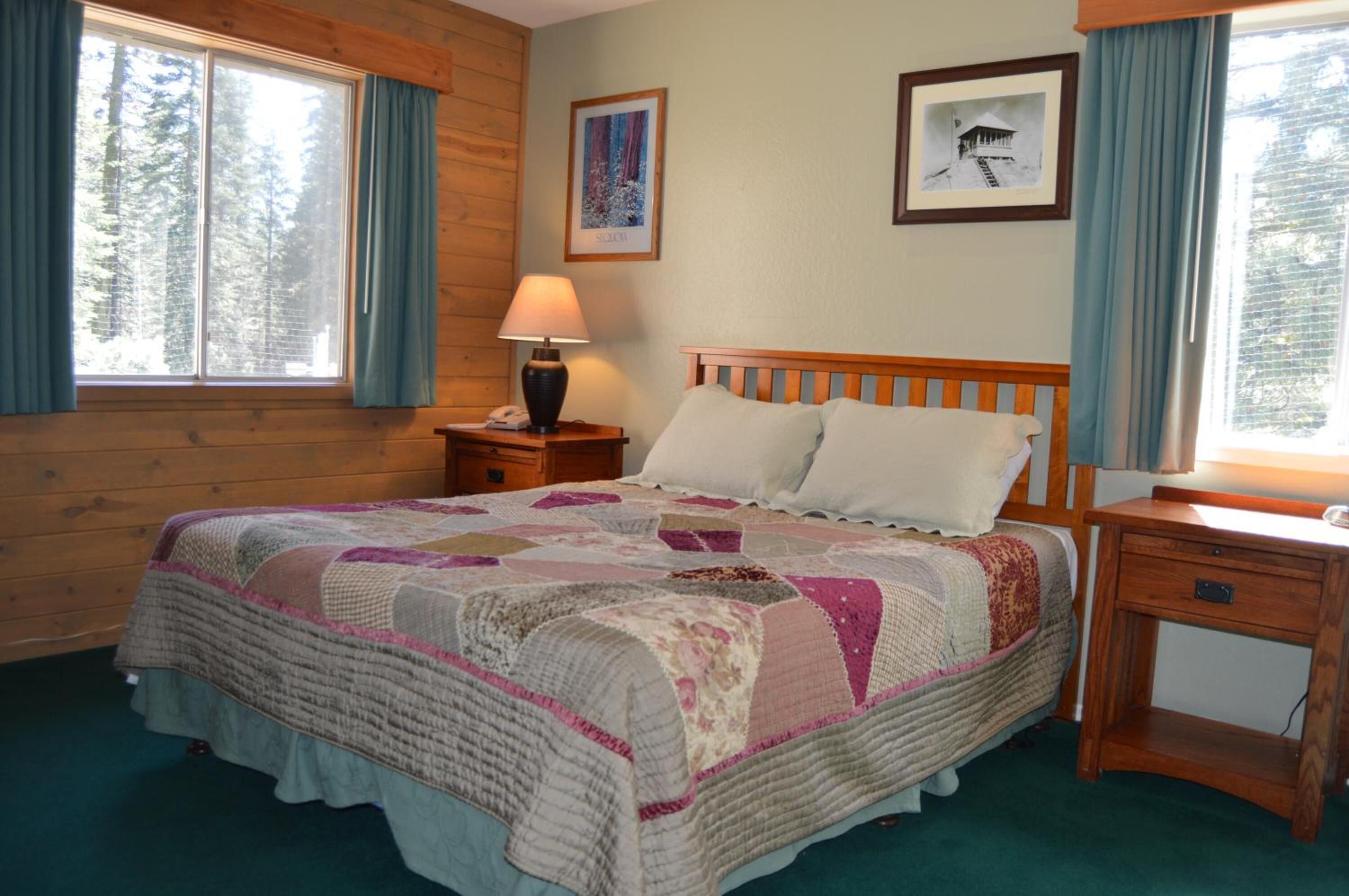 A bedroom with a wooden bed, a nightstand with a lamp, and a small desk.