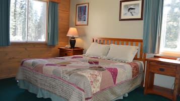 A bedroom with a wooden bed, a nightstand with a lamp, and a small desk.