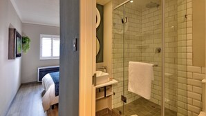Un bany modern amb dutxa de vidre, un lavabo blanc i una tovallola penjada a la paret.