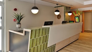 Zona d'entrada amb un disseny modern, que inclou una recepció, una planta en test i una càmera de seguretat penjada a la paret.
