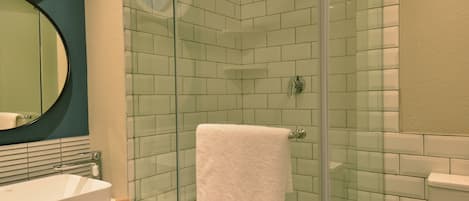 A modern bathroom with a glass-enclosed shower, a white sink, and a toilet.