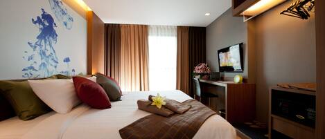 A hotel room with a large bed, a desk, a television, and a wall with a blue abstract painting.