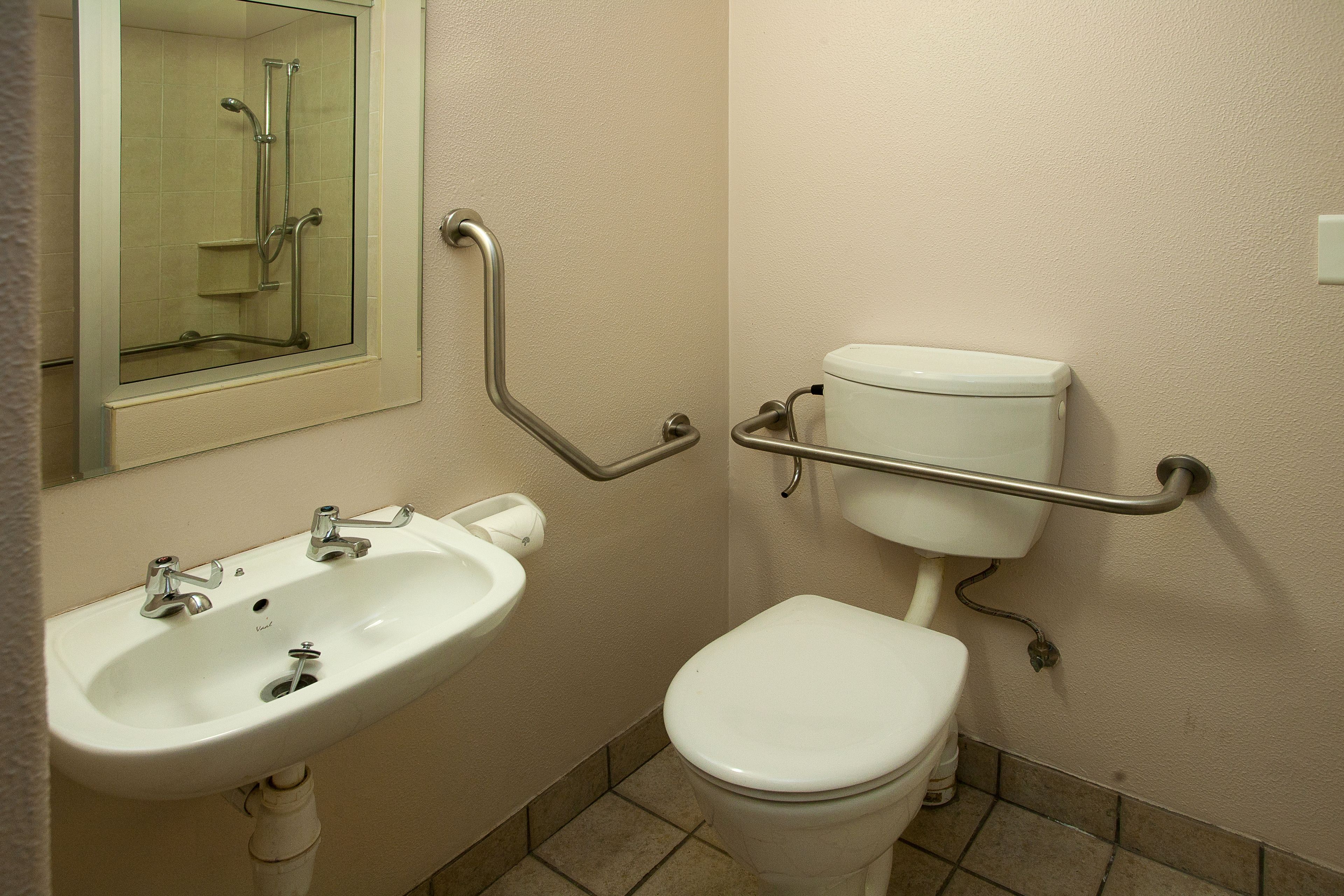 A bathroom with a white sink, toilet, and a glass-enclosed shower area.