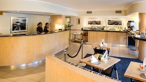 Um saguão de hotel com balcão de recepção, área de estar e espaço para refeições.