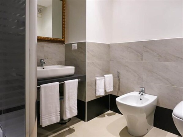 A modern bathroom with a sink, bidet, and towels. - La Locanda del Pino (Milan)