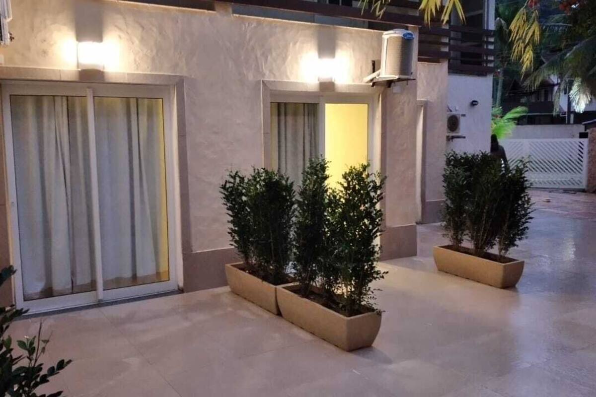 A modern building exterior with large sliding glass doors, potted plants, and a clean, tiled floor.