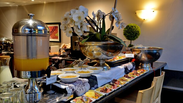 A buffet with various food items and a fruit juice dispenser.