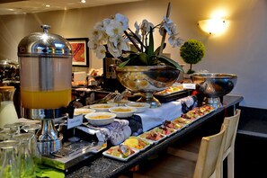 A buffet with various food items and a fruit juice dispenser.