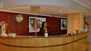 A reception desk with a sign instructing to return key cards on departure, a clock, and framed artwork on the wall.