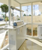 Un mostrador de recepción con una computadora, un teléfono y un ventanal que da a la calle y edificios.