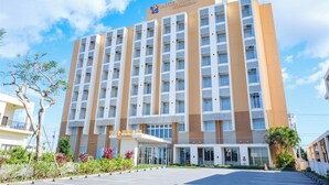 A multi-story hotel with a modern design, featuring a prominent entrance and a clear sky in the background. - Hotel Rising Sun Miyakojima (Miyakojima)