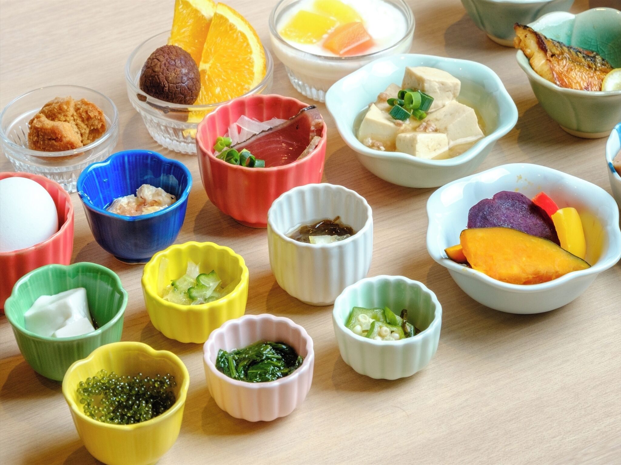 Plusieurs petits bols contenant différents types d’aliments sont disposés sur une table en bois.