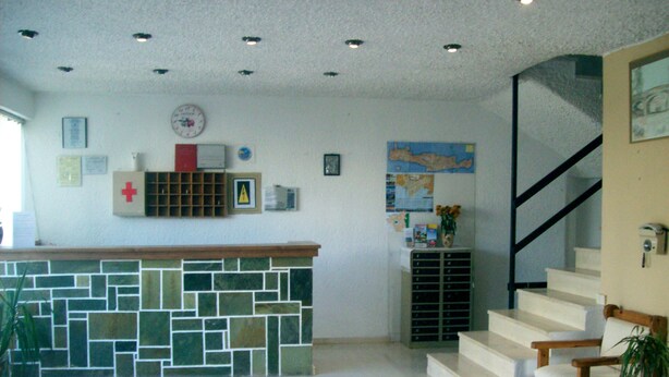 A reception area with a stone counter, a clock, a map, and a staircase. - Hotel Gefyra (Agios Nikolaos)