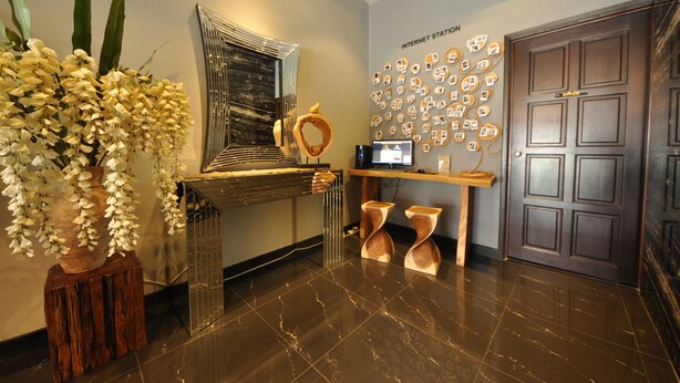 A modern reception area with a marble floor, a large mirror, a wall-mounted display of internet stations, and a wooden reception desk. - Le Metrotel (Ipoh)