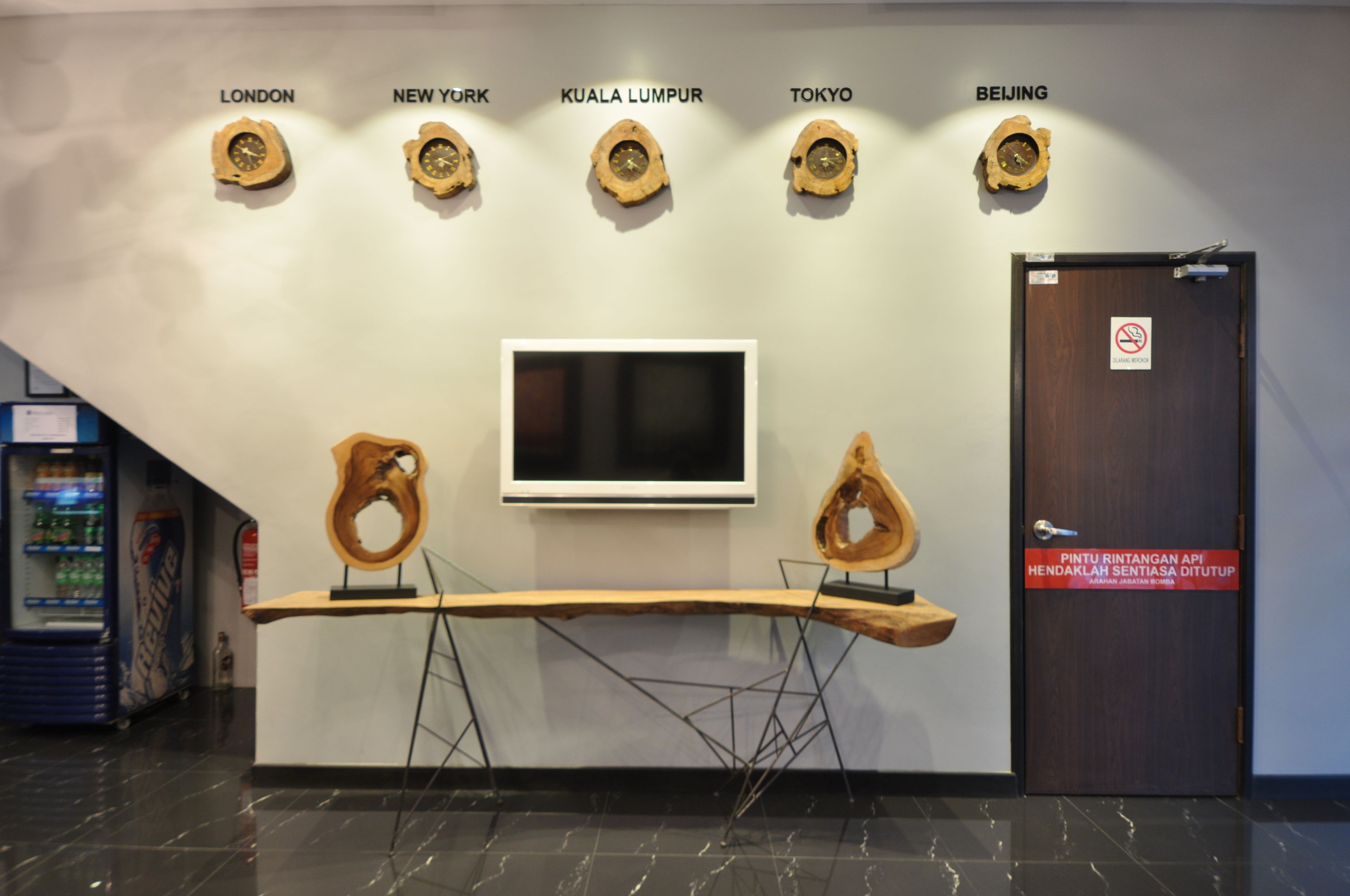 A reception desk with a mounted television and wooden wall clocks labeled with city names.