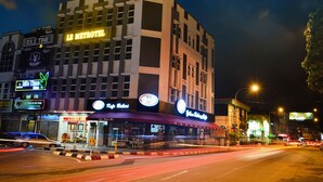 A multi-story hotel with a prominent 'Le Metrotel' sign, a restaurant with outdoor seating, and a visible street with light trails indicating traffic. - Le Metrotel (Ipoh)