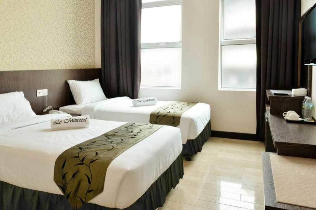 Una habitación de hotel con dos camas, un escritorio, una silla y un televisor.