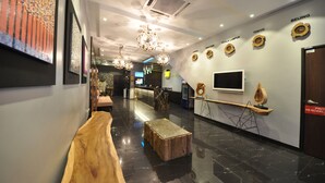 A modern hotel lobby with a wooden reception desk, a coffee table, and wall-mounted clocks indicating different cities. - Le Metrotel (Ipoh)