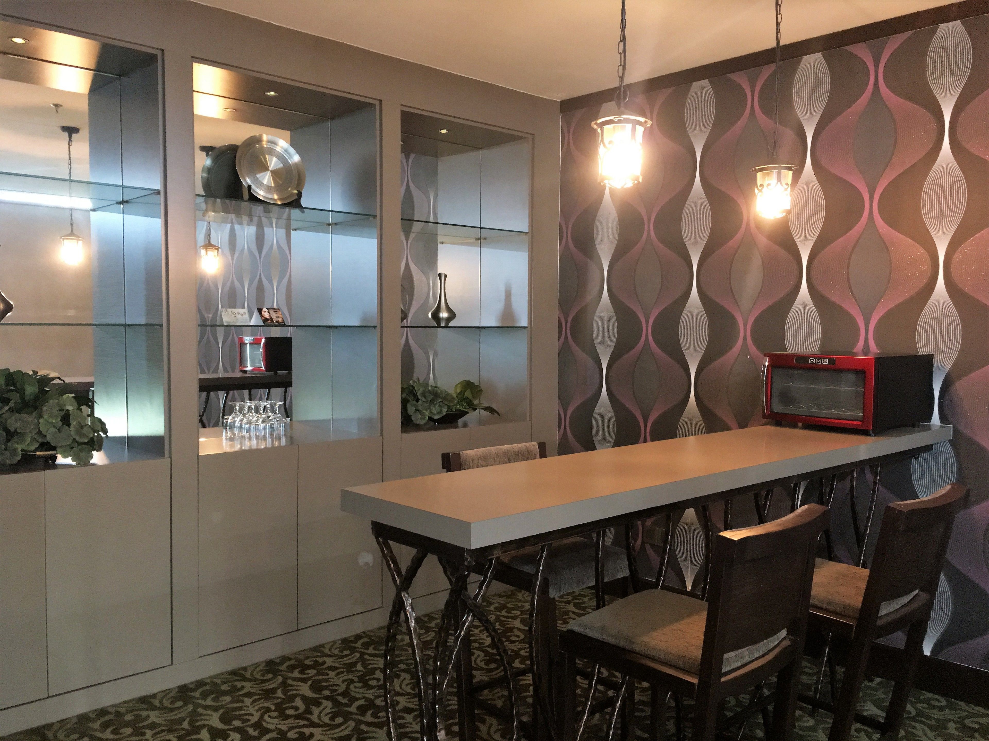 Una cocina moderna con una isla central, armarios con puertas de vidrio y un microondas en la pared.
