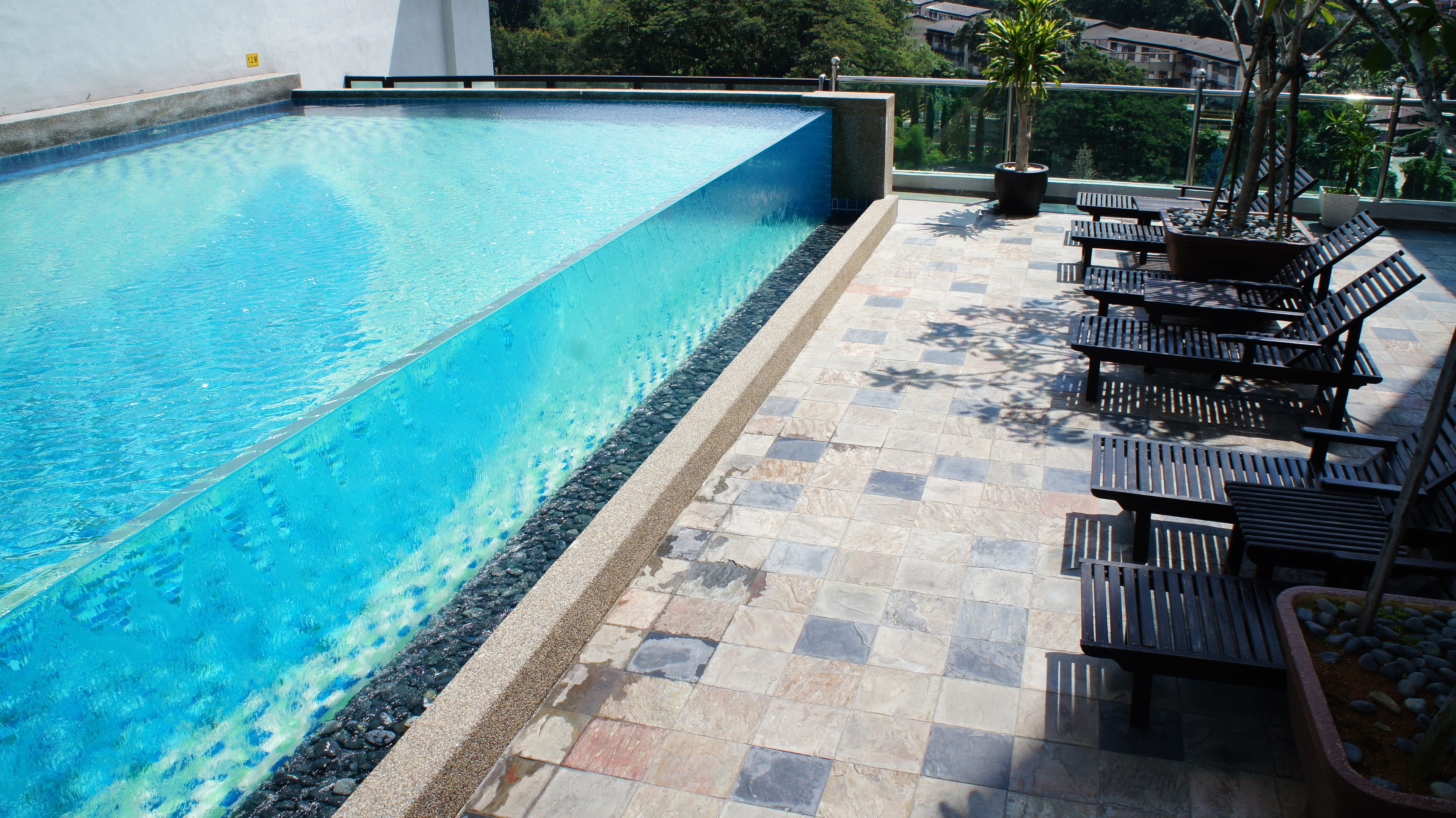 Una piscina con solárium de baldosas y bancos.