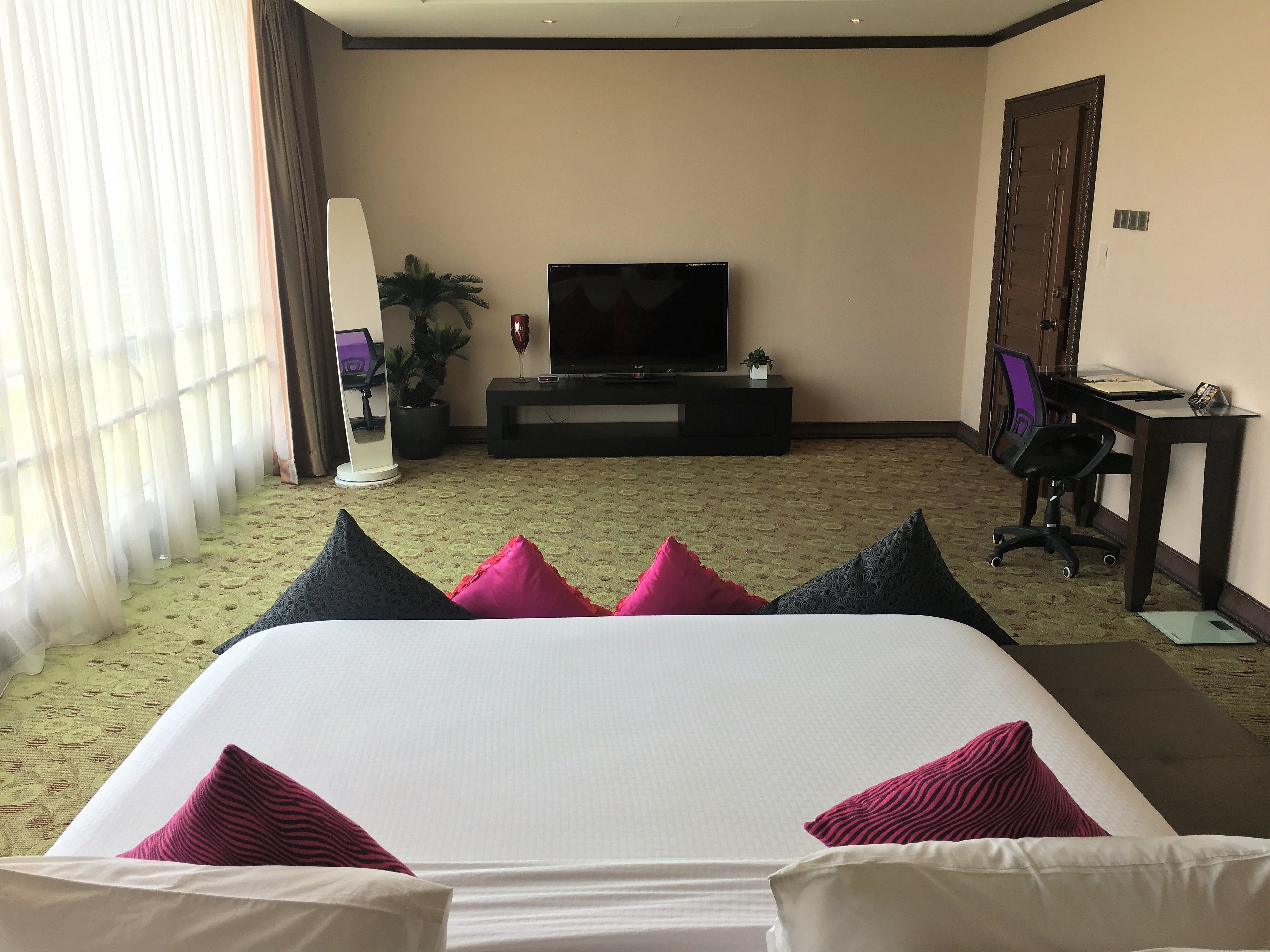 A hotel room with a bed, a TV, a desk, and a chair.
