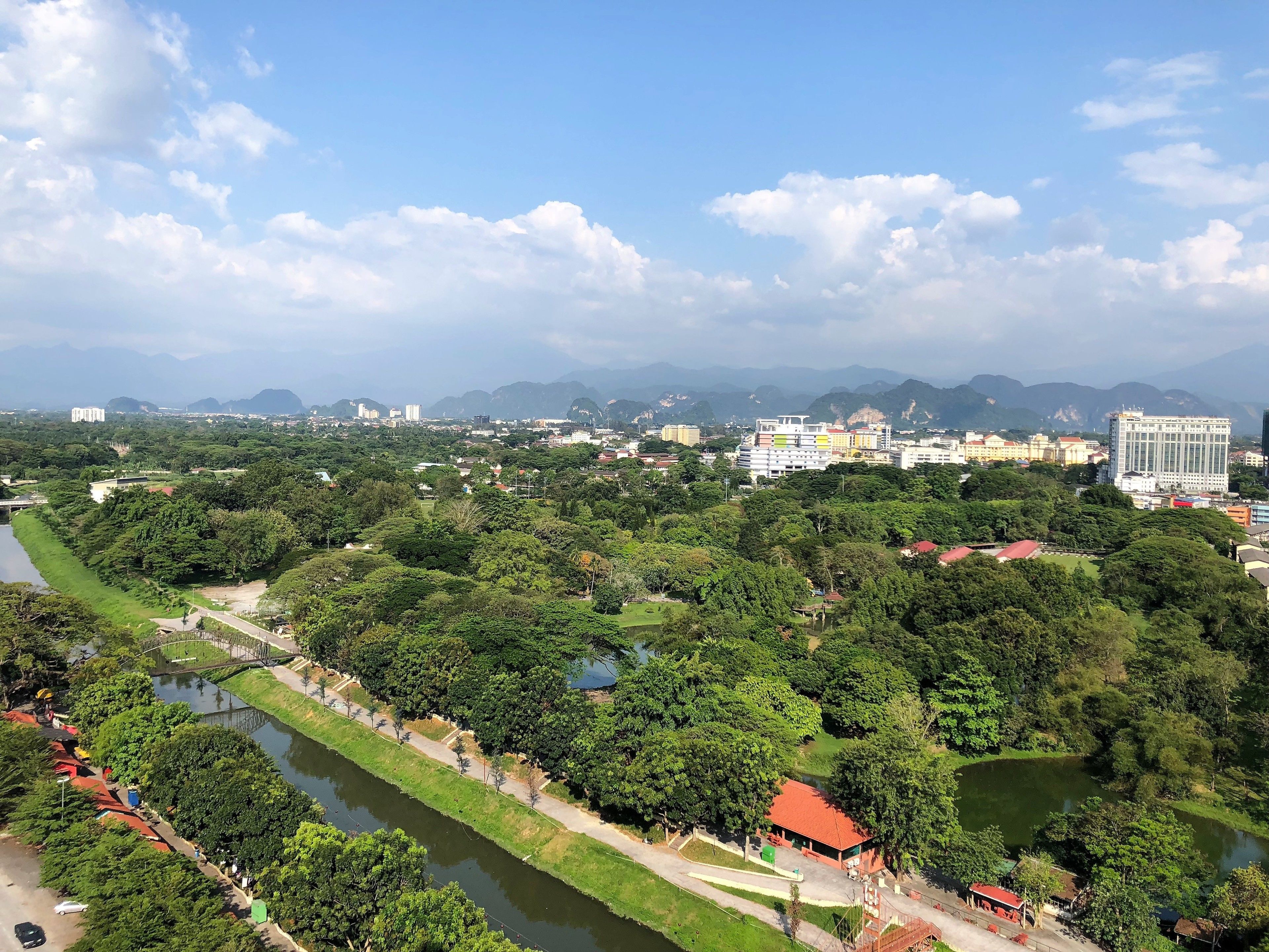 A cityscape with a river, green spaces, and various buildings including a prominent white building and a tall skyscraper.
