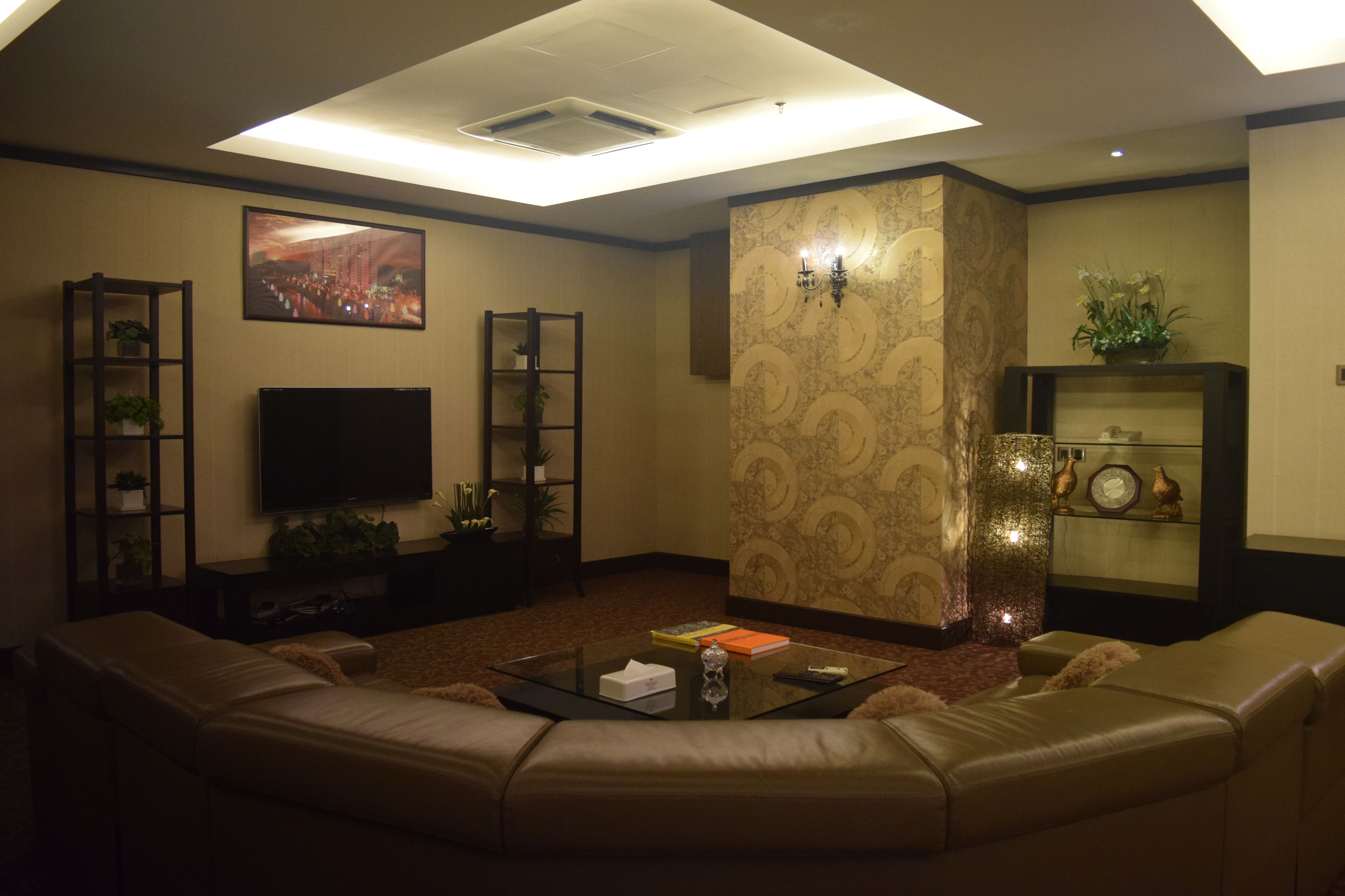 A living room with a sectional sofa, a flat-screen TV, and a coffee table with books and a vase.