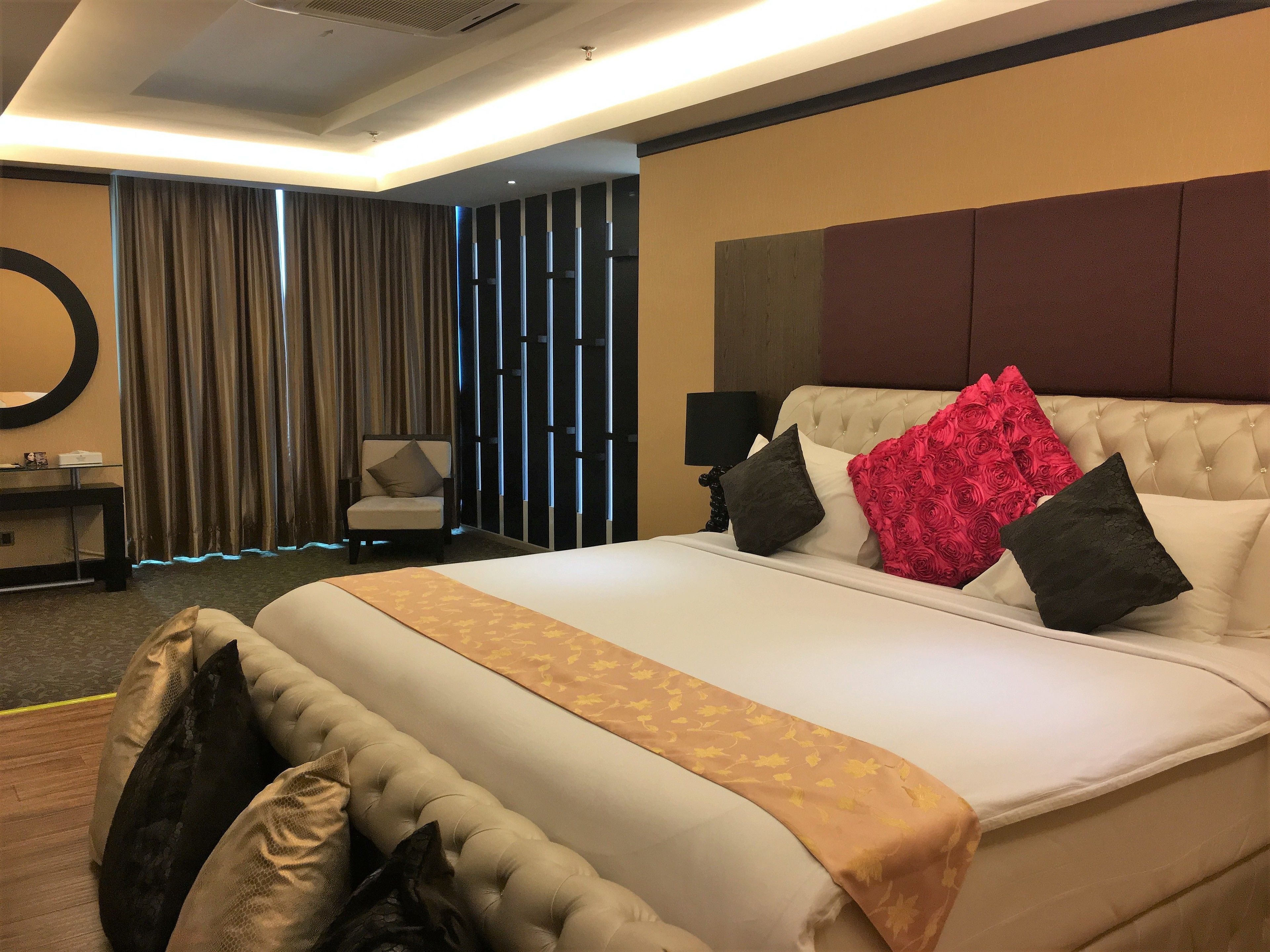 Een hotelkamer met een groot bed, een stoel, een bureau en een spiegel.