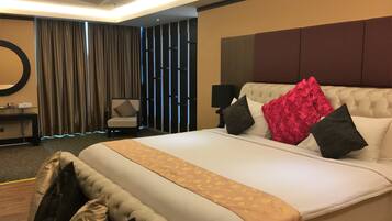 Een hotelkamer met een groot bed, een stoel, een bureau en een spiegel.