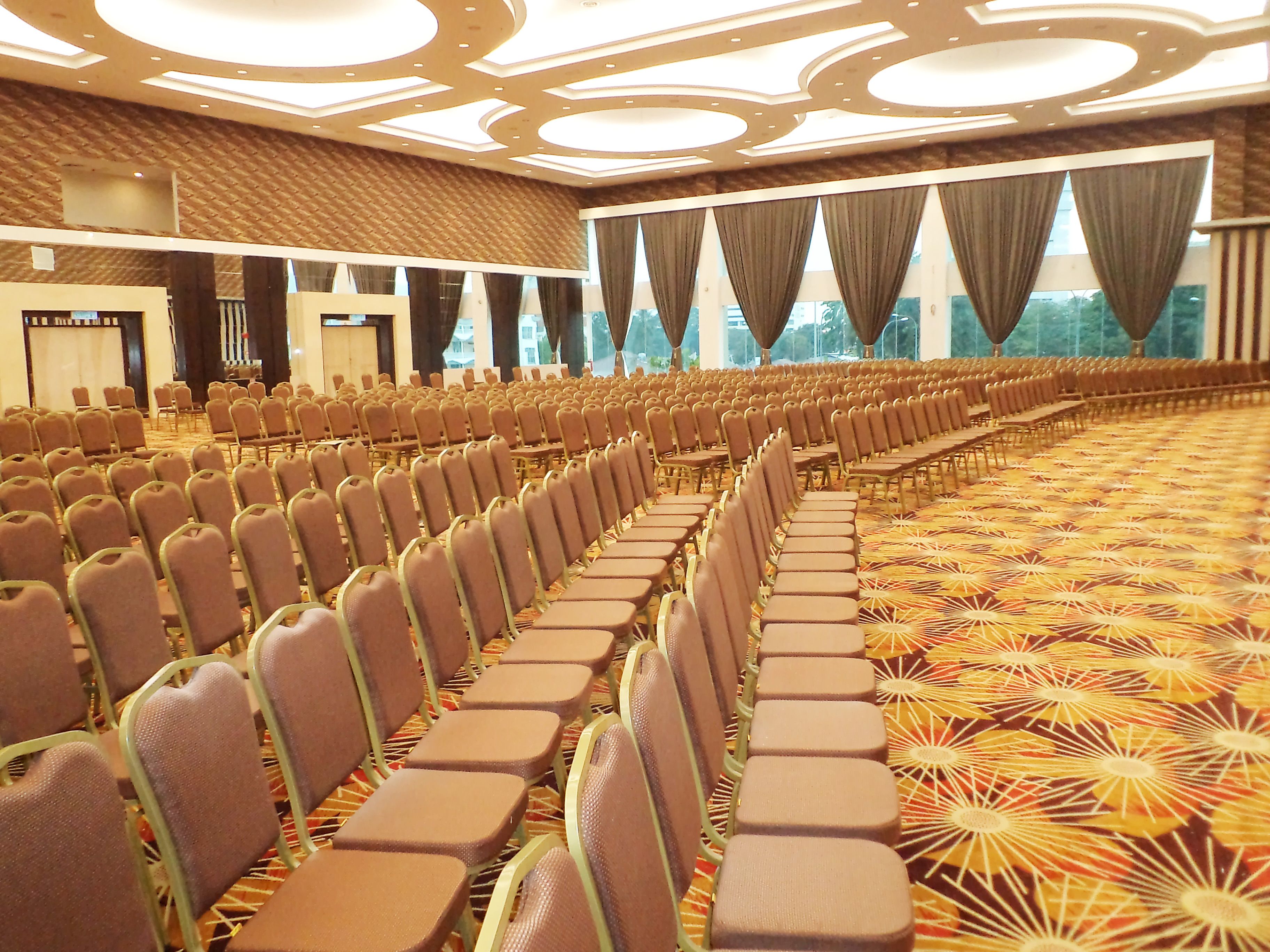 A conference room with rows of chairs, a patterned carpet, and a ceiling with recessed lighting.