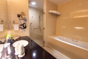 Un baño moderno con una bañera grande, ducha con mampara de vidrio y tocador con espejo y perchero.