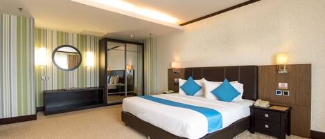 A hotel room with a large bed, bedside tables, a mirror, and a wardrobe.